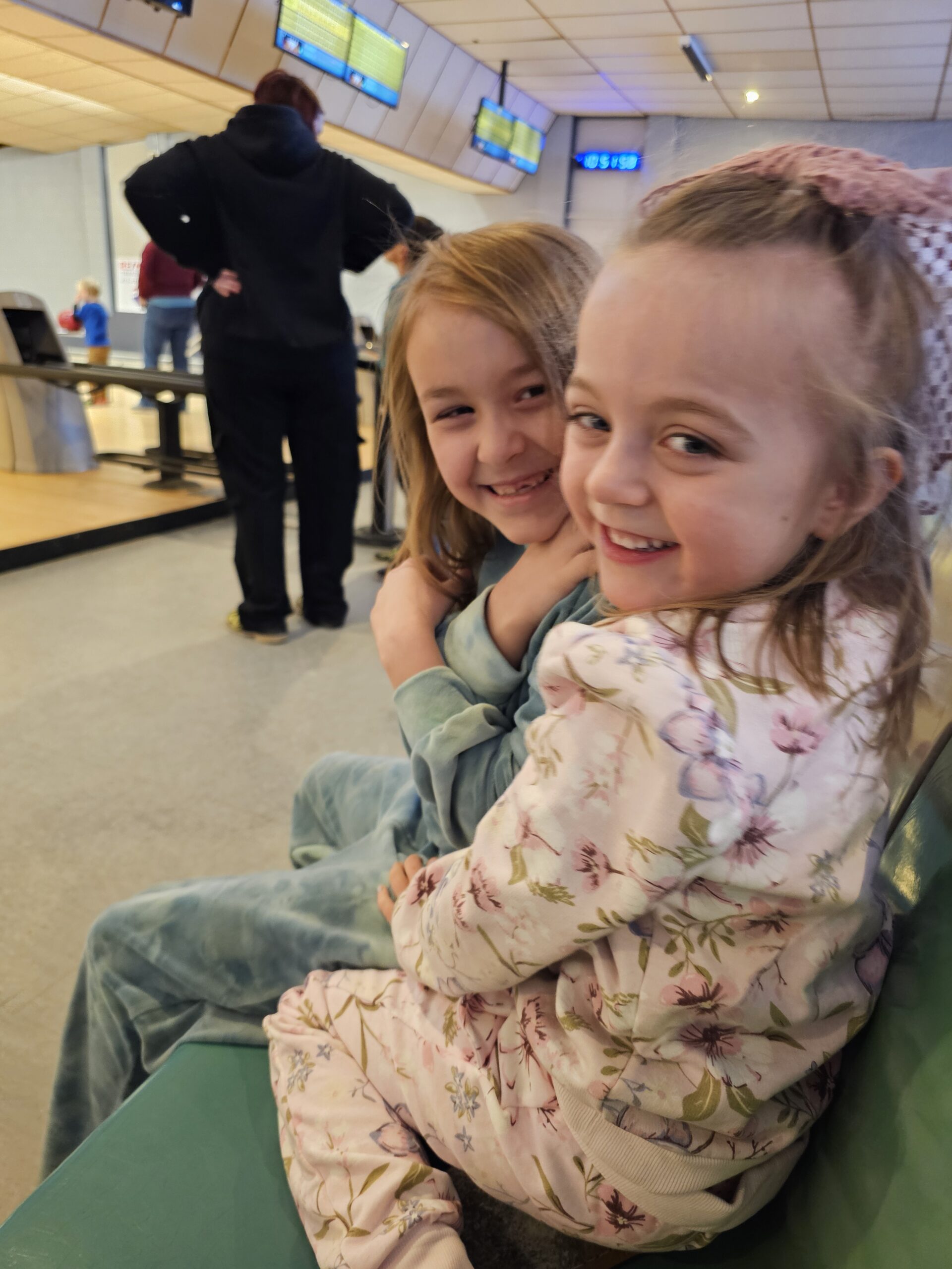 Two young friends smiling together during a bowling outing