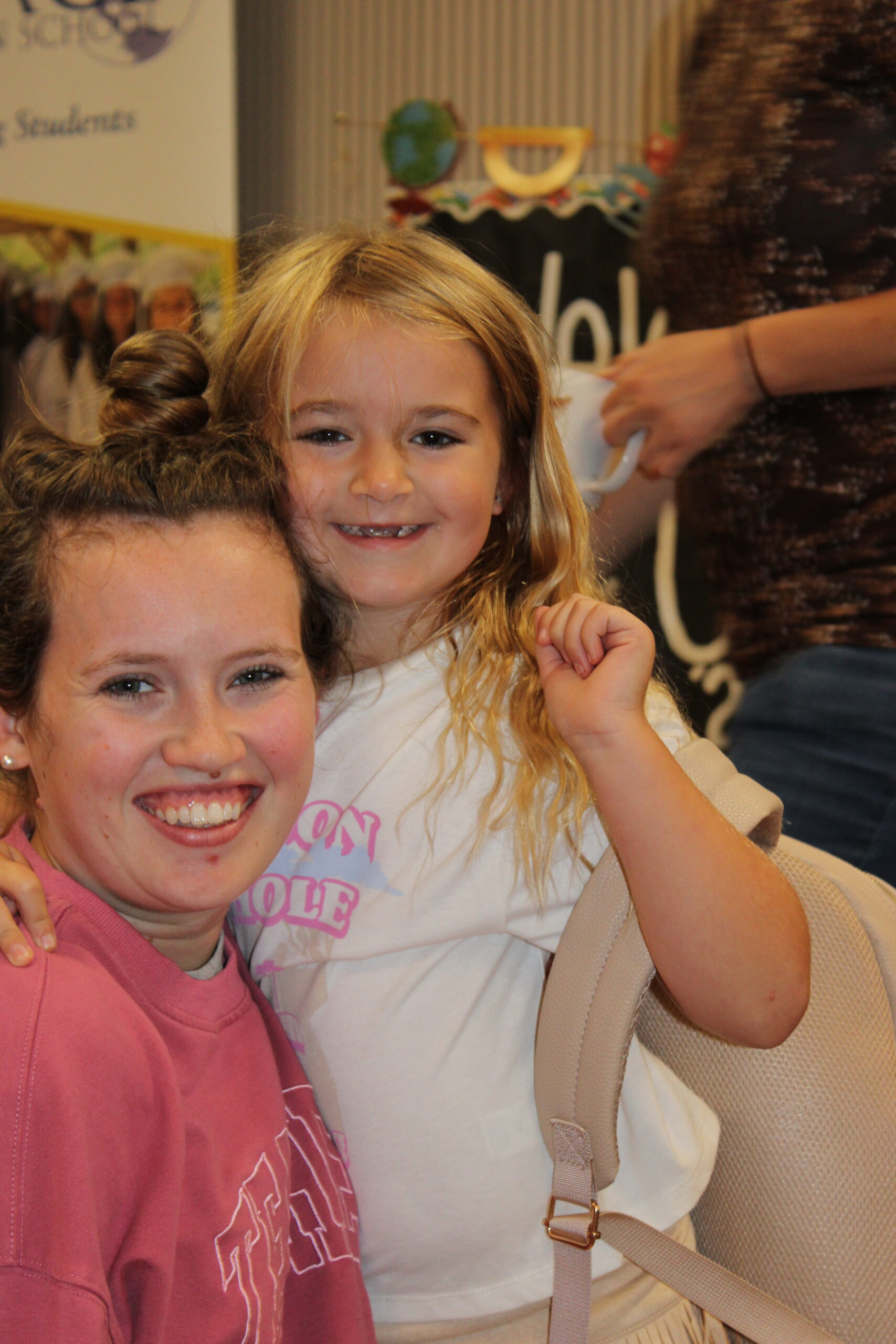 An older student and a young child smiling together at Grace